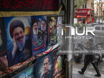 An Iranian man walks past posters featuring portraits of Lebanon's Hezbollah Secretary General, Hassan Nasrallah, and Iranian commander of t...