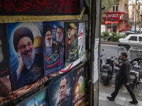 An Iranian man walks past posters featuring portraits of Lebanon's Hezbollah Secretary General, Hassan Nasrallah, and Iranian commander of t...