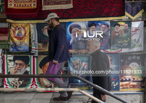 Iranian men walk past posters featuring portraits of Lebanon's Hezbollah Secretary General, Hassan Nasrallah, and Iranian commander of the I...