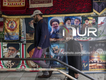 Iranian men walk past posters featuring portraits of Lebanon's Hezbollah Secretary General, Hassan Nasrallah, and Iranian commander of the I...