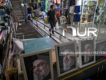 An Iranian man walks past framed portraits of Lebanon's Hezbollah Secretary General, Hassan Nasrallah, who was killed in an Israeli air stri...