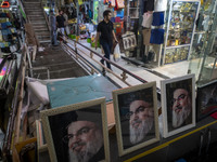 An Iranian man walks past framed portraits of Lebanon's Hezbollah Secretary General, Hassan Nasrallah, who was killed in an Israeli air stri...