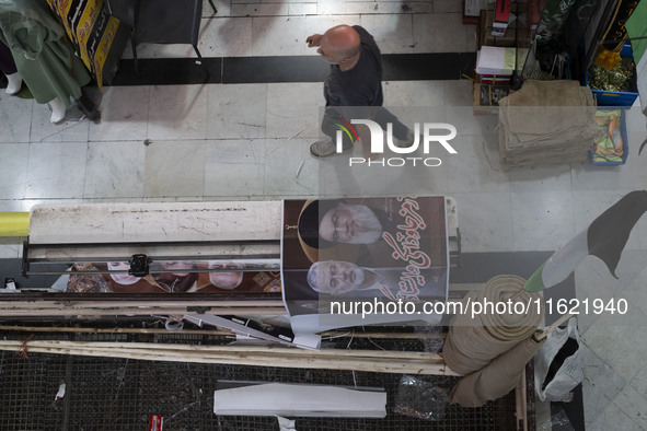 An Iranian man walks past a poster featuring portraits of Lebanon's Hezbollah Secretary General, Hassan Nasrallah, who was killed in an Isra...