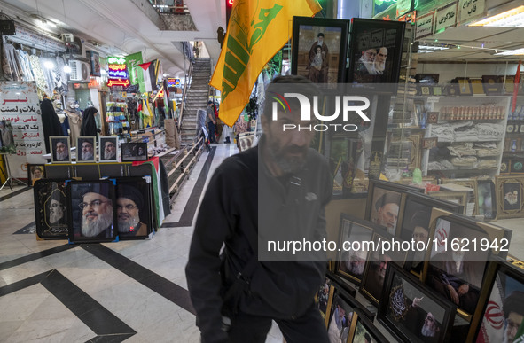 An Iranian man walks past framed portraits of Lebanon's Hezbollah Secretary General, Hassan Nasrallah, who was killed in an Israeli air stri...