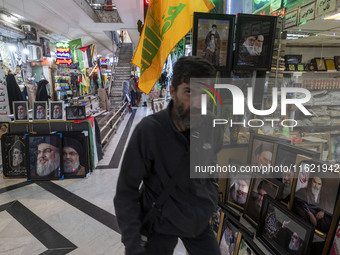 An Iranian man walks past framed portraits of Lebanon's Hezbollah Secretary General, Hassan Nasrallah, who was killed in an Israeli air stri...