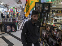 An Iranian man walks past framed portraits of Lebanon's Hezbollah Secretary General, Hassan Nasrallah, who was killed in an Israeli air stri...