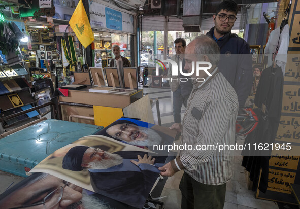 An Iranian man looks at portraits of Lebanon's Hezbollah Secretary General, Hassan Nasrallah, who is killed in an Israeli air strike in a su...