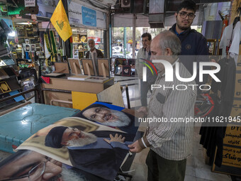 An Iranian man looks at portraits of Lebanon's Hezbollah Secretary General, Hassan Nasrallah, who is killed in an Israeli air strike in a su...