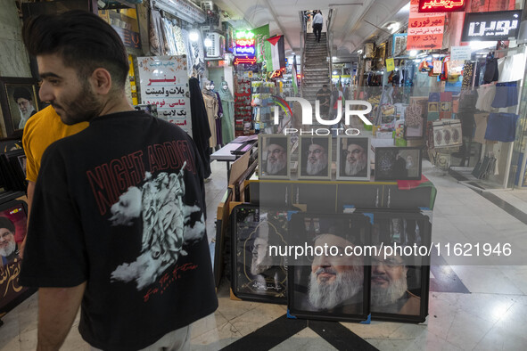 A young Iranian man stands next to framed portraits of Lebanon's Hezbollah Secretary General, Hassan Nasrallah, who was killed in an Israeli...