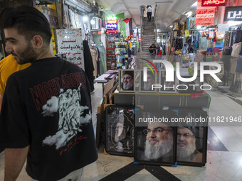 A young Iranian man stands next to framed portraits of Lebanon's Hezbollah Secretary General, Hassan Nasrallah, who was killed in an Israeli...