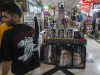 A young Iranian man stands next to framed portraits of Lebanon's Hezbollah Secretary General, Hassan Nasrallah, who was killed in an Israeli...