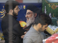 Two Iranian men stand in front of a portrait of Lebanon's Hezbollah Secretary General, Hassan Nasrallah, who was killed in an Israeli air st...