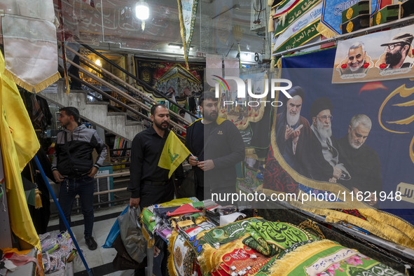 An Iranian man holds a flag of Lebanon's Hezbollah while shopping at a war toys and religious accessory shopping mall in downtown Tehran, Ir...