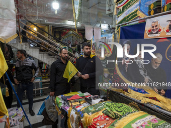 An Iranian man holds a flag of Lebanon's Hezbollah while shopping at a war toys and religious accessory shopping mall in downtown Tehran, Ir...