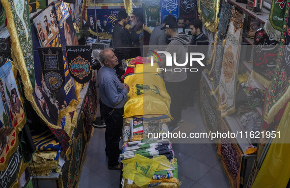 An elderly man stands next to a flag of Lebanon's Hezbollah at a flag shop in a war toys and religious accessory shopping mall in downtown T...