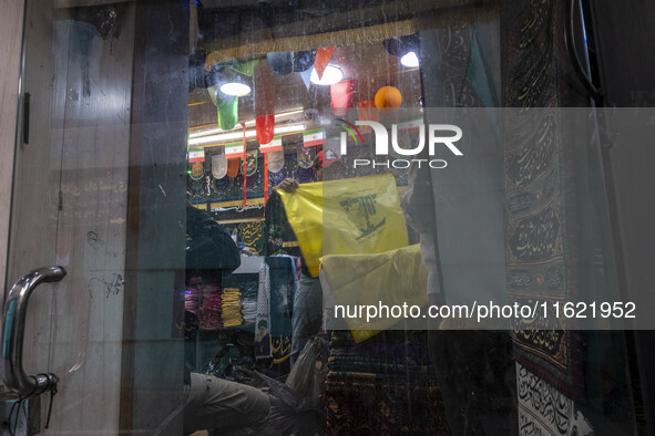 A worker holds a flag of Lebanon's Hezbollah at a flag and banner shop at a war toys and religious accessory shopping mall in downtown Tehra...