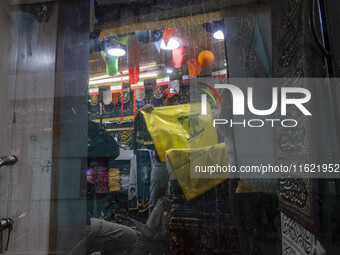 A worker holds a flag of Lebanon's Hezbollah at a flag and banner shop at a war toys and religious accessory shopping mall in downtown Tehra...