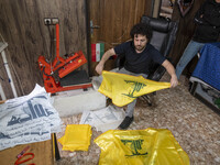 An Iranian worker holds a printed flag of Lebanon's Hezbollah at a flag and banner printing workshop at a war toys and religious accessory s...