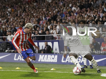 Vinicius Jr of Real Madrid and Rodrigo De Paul of Atletico de Madrid fight for the ball during the La Liga 2024/25 match between Atletico de...