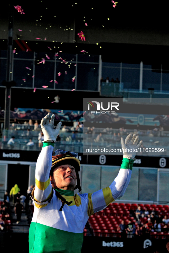 Jockey Justin Stein tosses flowers from a garland after a win in the 134th running of the $400,000 Breeders' Stakes, the third race of the O...