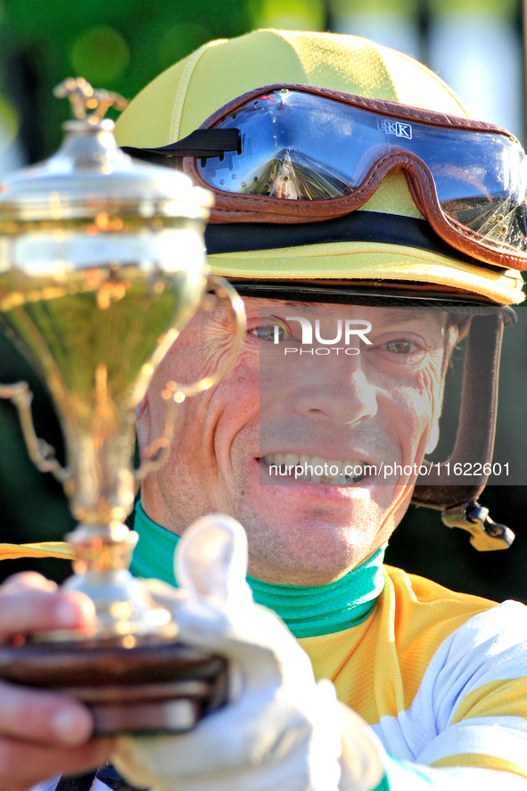 Jockey Justin Stein holds the trophy while celebrating in the winner's circle after riding Roscar to a win in the 134th running of the $400,...