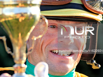 Jockey Justin Stein holds the trophy while celebrating in the winner's circle after riding Roscar to a win in the 134th running of the $400,...