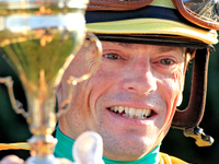 Jockey Justin Stein holds the trophy while celebrating in the winner's circle after riding Roscar to a win in the 134th running of the $400,...