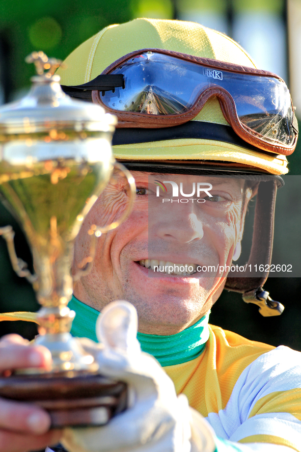 Jockey Justin Stein holds the trophy while celebrating in the winner's circle after riding Roscar to a win in the 134th running of the $400,...