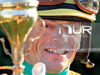 Jockey Justin Stein holds the trophy while celebrating in the winner's circle after riding Roscar to a win in the 134th running of the $400,...