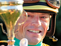 Jockey Justin Stein holds the trophy while celebrating in the winner's circle after riding Roscar to a win in the 134th running of the $400,...