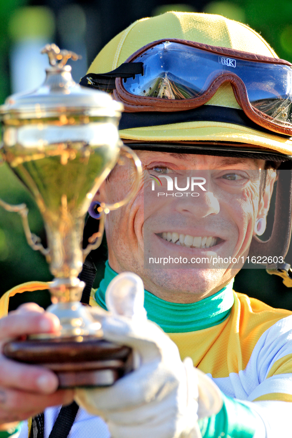 Jockey Justin Stein holds the trophy while celebrating in the winner's circle after riding Roscar to a win in the 134th running of the $400,...