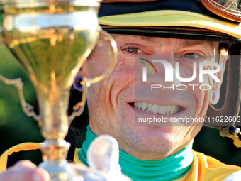 Jockey Justin Stein holds the trophy while celebrating in the winner's circle after riding Roscar to a win in the 134th running of the $400,...