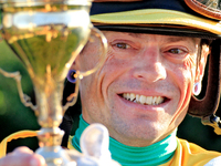 Jockey Justin Stein holds the trophy while celebrating in the winner's circle after riding Roscar to a win in the 134th running of the $400,...