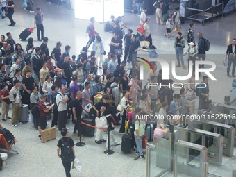 Passengers wait at the waiting hall of Hangzhou East Railway Station in Hangzhou, China, on September 30, 2024. On the day before the Nation...