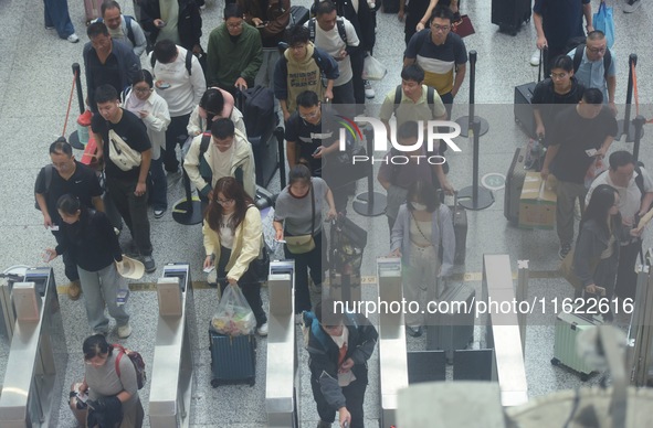 Passengers wait at the waiting hall of Hangzhou East Railway Station in Hangzhou, China, on September 30, 2024. On the day before the Nation...