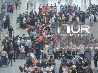 Passengers wait at the waiting hall of Hangzhou East Railway Station in Hangzhou, China, on September 30, 2024. On the day before the Nation...