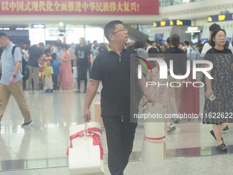 Passengers wait at the waiting hall of Hangzhou East Railway Station in Hangzhou, China, on September 30, 2024. On the day before the Nation...