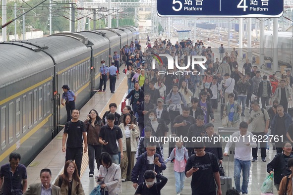 Passengers get off the train at Yantai Station in Yantai, China, on September 30, 2024. According to the China National Railway Group Co., L...