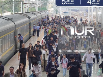 Passengers get off the train at Yantai Station in Yantai, China, on September 30, 2024. According to the China National Railway Group Co., L...