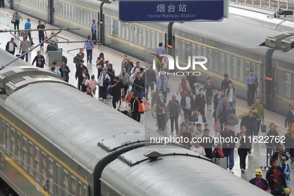 Passengers get off the train at Yantai Station in Yantai, China, on September 30, 2024. According to the China National Railway Group Co., L...