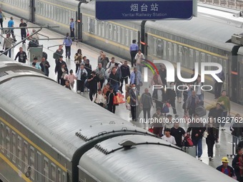 Passengers get off the train at Yantai Station in Yantai, China, on September 30, 2024. According to the China National Railway Group Co., L...