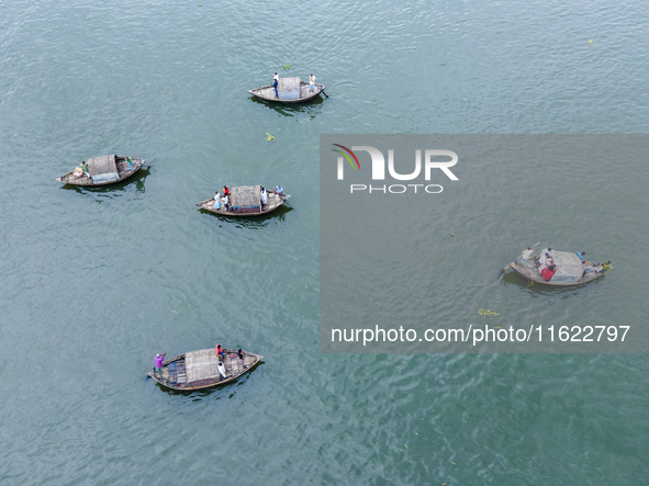 An aerial view shows boatmen navigating their vessel across the Shitalakshya River, carrying passengers from Bandar Ghat in Narayanganj, Ban...