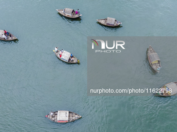 An aerial view shows boatmen navigating their vessel across the Shitalakshya River, carrying passengers from Bandar Ghat in Narayanganj, Ban...