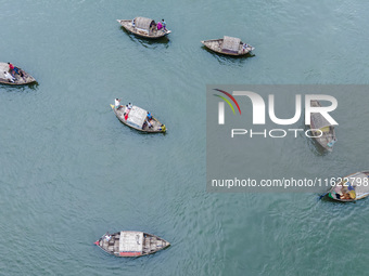 An aerial view shows boatmen navigating their vessel across the Shitalakshya River, carrying passengers from Bandar Ghat in Narayanganj, Ban...