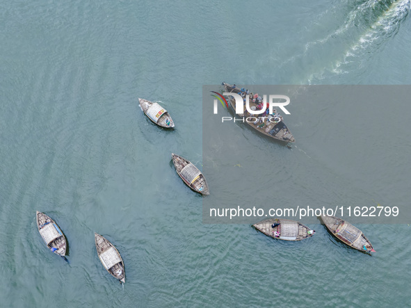 An aerial view shows boatmen navigating their vessel across the Shitalakshya River, carrying passengers from Bandar Ghat in Narayanganj, Ban...