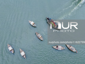 An aerial view shows boatmen navigating their vessel across the Shitalakshya River, carrying passengers from Bandar Ghat in Narayanganj, Ban...