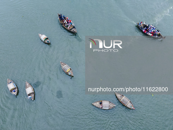 An aerial view shows boatmen navigating their vessel across the Shitalakshya River, carrying passengers from Bandar Ghat in Narayanganj, Ban...