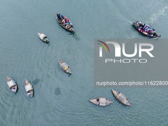 An aerial view shows boatmen navigating their vessel across the Shitalakshya River, carrying passengers from Bandar Ghat in Narayanganj, Ban...