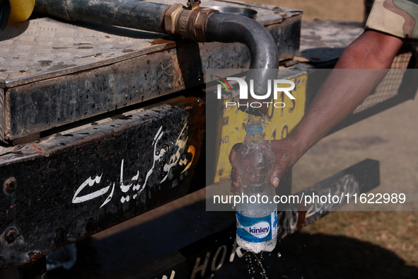 A paramilitary soldier fills water in a bottle as Kashmiri polling officials carry sealed Electronic Voting Machines (EVM) and Voter Verifia...