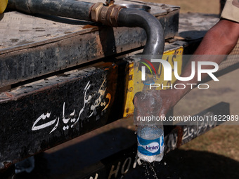 A paramilitary soldier fills water in a bottle as Kashmiri polling officials carry sealed Electronic Voting Machines (EVM) and Voter Verifia...